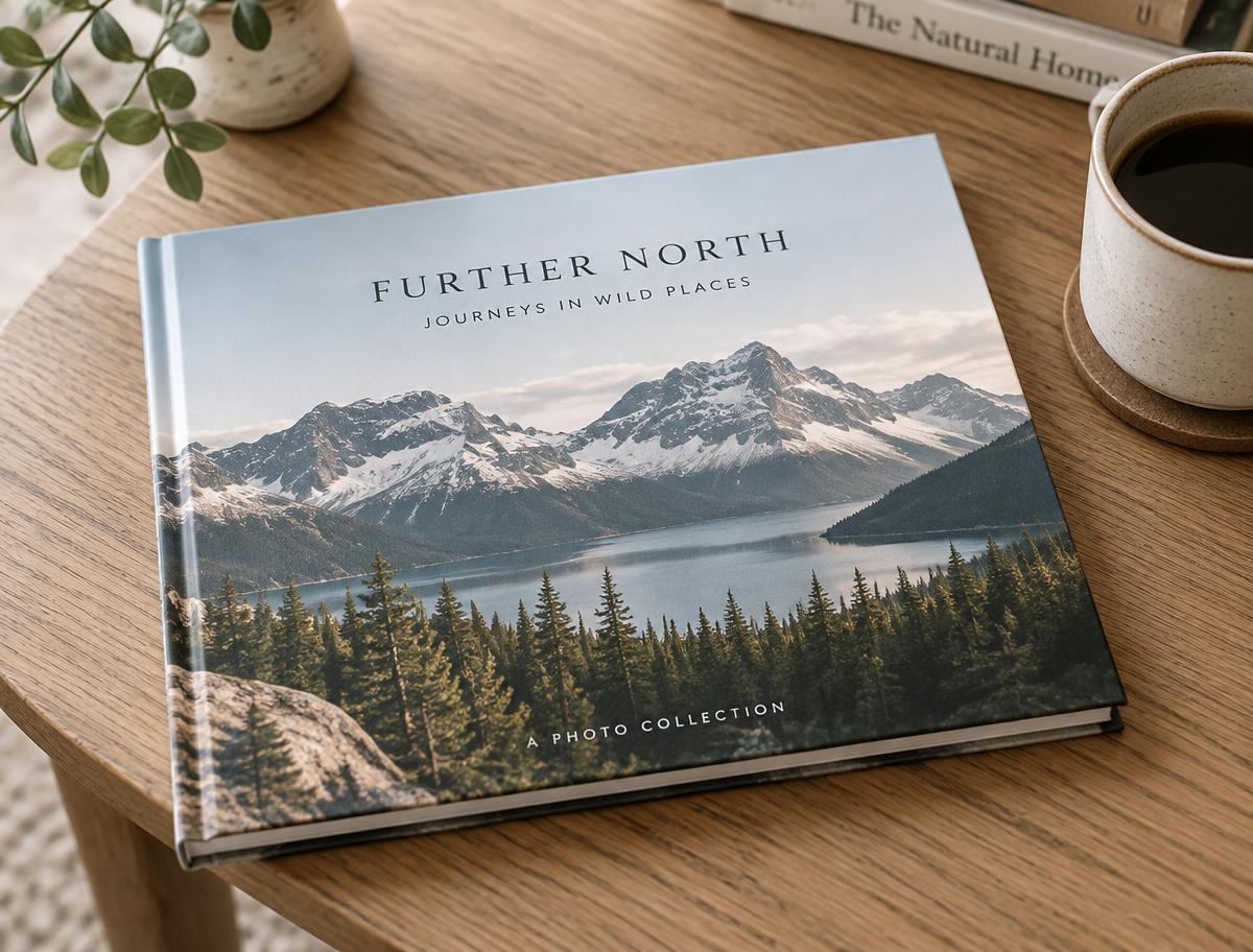 Closed landscape hardcover photo book with a mountain lake cover on an oak table